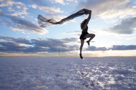 Téléchargez les photos : Une belle femme danse gracieusement sur la plage au bord de la mer un jour d'été, ses mouvements fluides et sans effort, incarnant l'essence de la joie et de la liberté. - en image libre de droit