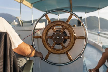 Photo for Man at the steering wheel of a sailboat. Man Holding Hands on ship rudder and navigates. - Royalty Free Image
