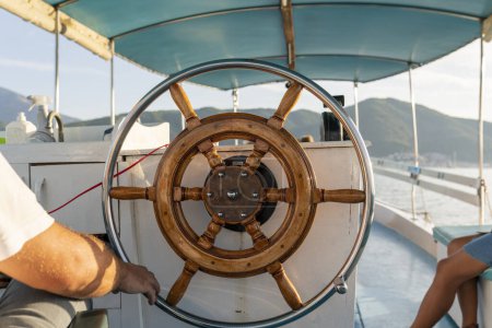 Photo for Man at the steering wheel of a sailboat. Man Holding Hands on ship rudder and navigates. - Royalty Free Image