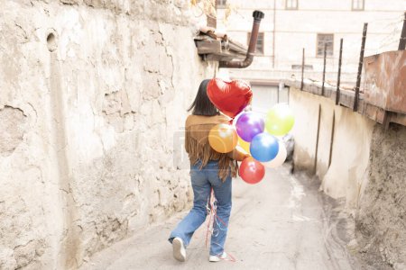 Téléchargez les photos : Jeune femme tenant un tas de ballons en ville, vue arrière - en image libre de droit