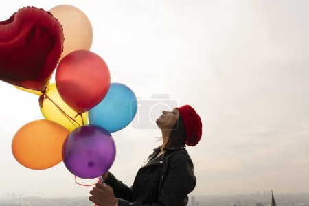 Téléchargez les photos : Jeune femme au béret rouge tenant un tas de ballons - en image libre de droit