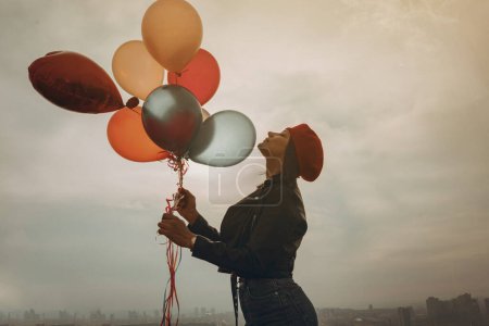 Photo for Young woman in red beret holding a bunch of balloons - Royalty Free Image