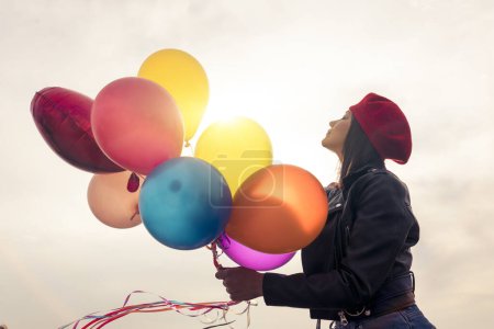 Foto de Mujer joven en boina roja sosteniendo un montón de globos - Imagen libre de derechos