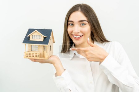 Téléchargez les photos : Jeune femme caucasienne tenant un modèle de maison isolé sur fond blanc - en image libre de droit
