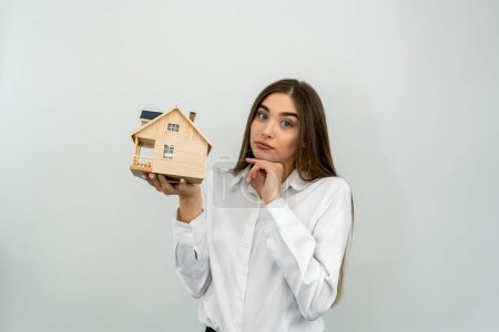 Téléchargez les photos : Jeune femme caucasienne tenant un modèle de maison isolé sur fond blanc - en image libre de droit