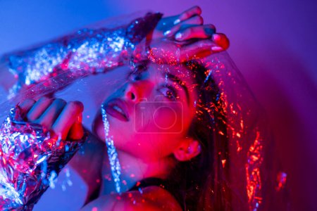 Photo for High Fashion model woman in colorful bright neon blue and purple lights posing in studio. Portrait of beautiful girl with trendy glowing make-up. Art design vivid style On colourful vivid background - Royalty Free Image