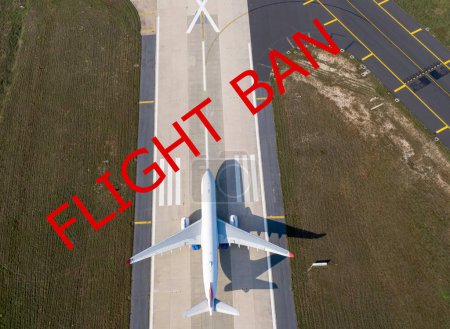 flight ban red text against parked plane in airport  