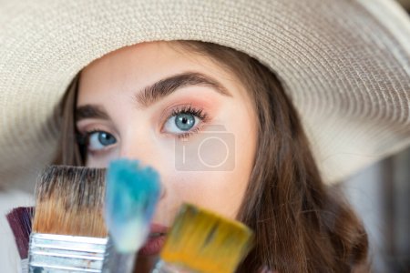Photo for Portrait of beautiful girl in straw hat  with art brushes - Royalty Free Image