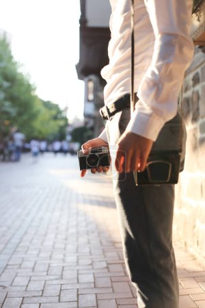 Téléchargez les photos : Jeune homme avec vieil appareil photo en ville - en image libre de droit