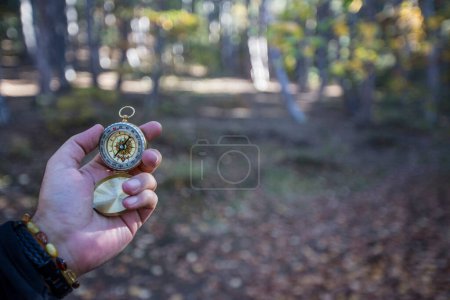 Téléchargez les photos : Main tenant boussole dorée sur fond de nature - en image libre de droit