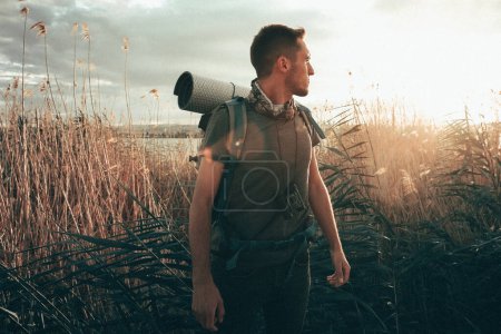 Photo for Young man hiking with backpack at the sunset - Royalty Free Image
