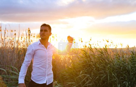Photo for Young man with fist up  in the field at  sunset - Royalty Free Image