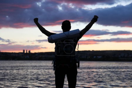 Foto de Joven con mochila con las manos levantadas en el fondo del lago. - Imagen libre de derechos