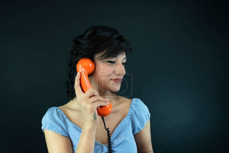 Téléchargez les photos : Jeune femme parlant sur Orange téléphone rétro. Vintage fille parler broche jusqu'à téléphone - en image libre de droit