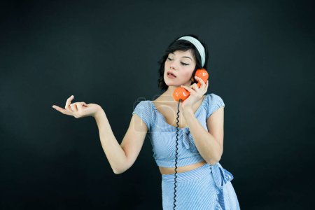 Téléchargez les photos : Jeune femme parlant sur Orange téléphone rétro. Vintage fille parler broche jusqu'à téléphone - en image libre de droit