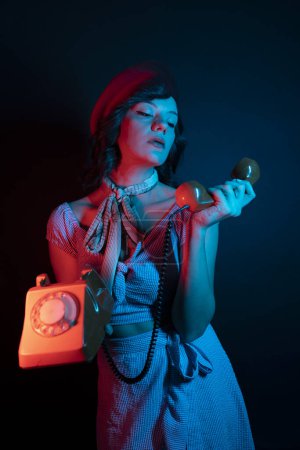 Foto de Mujer joven hablando en Orange Retro Phone. Mujer modelo de alta moda en colores brillantes luces de neón azul y púrpura posando en el estudio. - Imagen libre de derechos