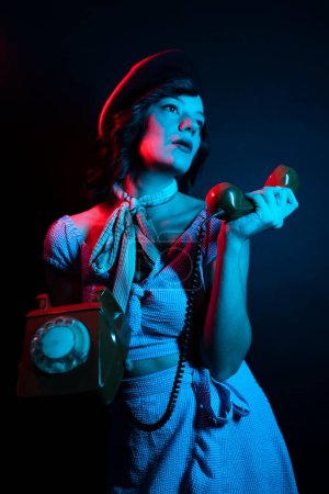 Photo for Young Woman Talking on Orange Retro Phone. High Fashion model woman in colorful bright neon blue and purple lights posing in studio. - Royalty Free Image