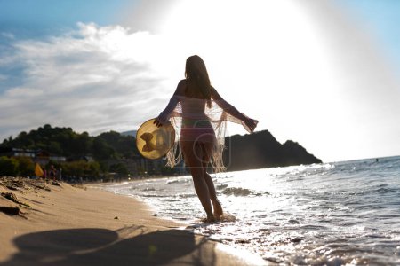 Foto de Mujer feliz caminando en la playa al atardecer. Hermosa mujer feliz relajarse caminando en la playa cerca del mar al atardecer en la noche. - Imagen libre de derechos