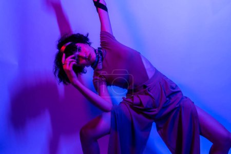 Foto de Mujer modelo de alta moda en luces coloridas de color azul neón y púrpura posando en el estudio. Retrato de mujer hermosa con maquillaje brillante de moda. Diseño de arte estilo vívido - Imagen libre de derechos