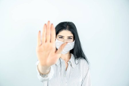 Téléchargez les photos : Jeune femme avec masque chirurgical sur le visage contre le SRAS-CoV-2. femme portant un masque de santé montrant stop signe - en image libre de droit
