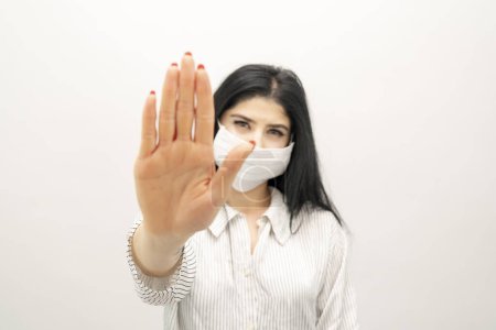 Photo for Young woman with surgical mask on face against SARS-CoV-2. woman wearing health mask showing stop sign - Royalty Free Image