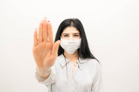 Photo for Young woman with surgical mask on face against SARS-CoV-2. woman wearing health mask showing stop sign - Royalty Free Image