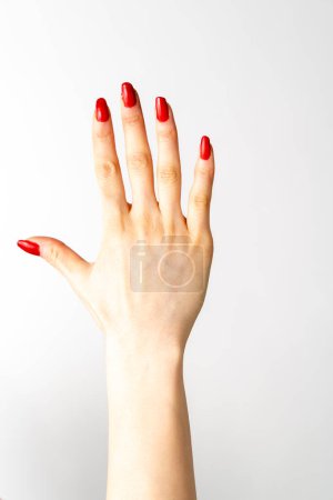 Photo for A woman's hand with a red nail polish on it. woman's hand showing the number five white background - Royalty Free Image