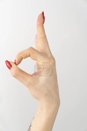Foto de Una mano con esmalte de uñas rojo hace un signo okey - Imagen libre de derechos