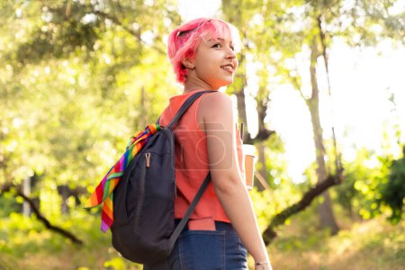 Téléchargez les photos : Une jeune touriste aux cheveux roses regarde son sac à dos et voyage dans la nature - en image libre de droit