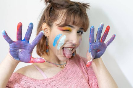 Téléchargez les photos : Femme heureuse cachant le visage avec ses mains peintes. Créatif, art, enfance, concept de dessin - en image libre de droit