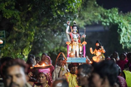 Foto de Ídolo Shiv llevando en la cabeza por una señora y algunas personas que llevan ídolo dioses en la cabeza, durante el festival indio diwali en la aldea india. - Imagen libre de derechos
