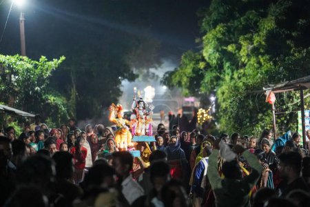 Foto de KACHANDA, CHHATTISGARH, INDIA, 15 DE NOVIEMBRE DE 2022: ídolo Shiv llevando en la cabeza por una señora y algunas personas llevando ídolo dioses en la cabeza, durante el festival indio diwali en la aldea india. - Imagen libre de derechos