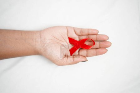 Téléchargez les photos : Une femme tenant un ruban rouge dans une main représentant la Journée mondiale du sida, le concept de santé, la sensibilisation au VIH / sida - en image libre de droit
