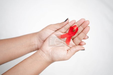 Téléchargez les photos : Mondes Journée mondiale du sida 2022-2023, mains rapprochées tenant un ruban rouge de sensibilisation au sida sur fond blanc concept de journée mondiale du sida VIH - en image libre de droit