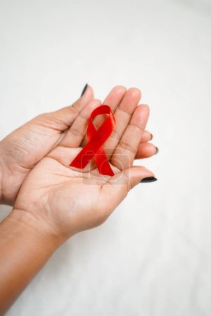 Téléchargez les photos : Mondes Journée mondiale du sida 2022-2023, mains rapprochées tenant un ruban rouge de sensibilisation au sida sur fond blanc concept de journée mondiale du sida VIH - en image libre de droit