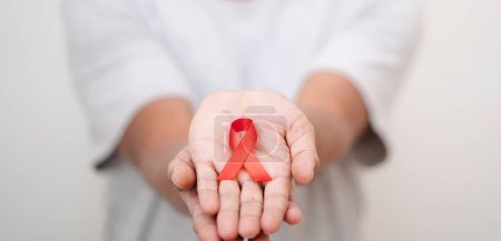 Téléchargez les photos : Mains féminines avec ruban rouge de sensibilisation au sida, badge VIH sida pour diffuser le concept de sensibilisation au VIH sida, soins de santé, médecine et sensibilisation au sida. - en image libre de droit
