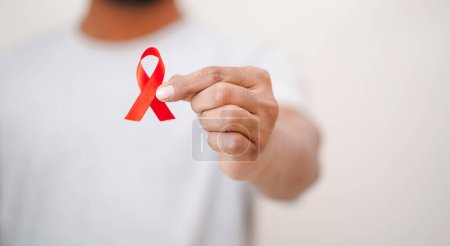 Téléchargez les photos : Mondes Journée mondiale du sida, Les hommes tiennent un ruban rouge Dans sa main, Sensibilisation au VIH / sida, Gros plan sur les hommes tenant un ruban rouge sur fond blanc Concept VIH / sida, Concept Santé - en image libre de droit