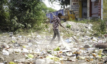 Foto de Diciembre, 2022, Raipur, India: Hombre barriendo la basura con escoba y polietileno gran área de basura, Hombre limpiando el área contaminada, Día de control de contaminación, concepto de contaminación - Imagen libre de derechos