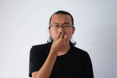Photo for Adult Asian man wearing black t-shirt and eyeglasses with long hair covering the nose in grey background. - Royalty Free Image