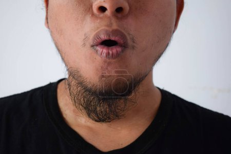 Photo for Adult Asian man wearing black t-shirt and eyeglasses with long hair feels stress, shock or frustrated in grey background. - Royalty Free Image