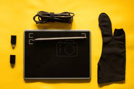 Photo for Electronic drawing pen tablet stylus and accessories usb convert port, glove, and cable isolated yellow background - Royalty Free Image