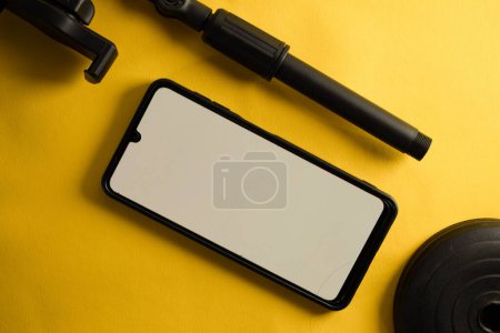 Téléchargez les photos : Vue du haut du smartphone avec écran blanc et parties de téléphone stand ou mini trépied isolé sur fond jaune - en image libre de droit
