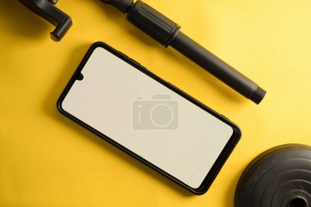 Téléchargez les photos : Vue du haut du smartphone avec écran blanc et parties de téléphone stand ou mini trépied isolé sur fond jaune - en image libre de droit