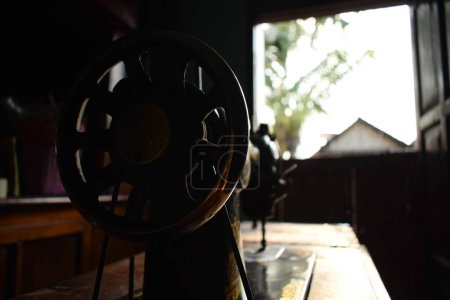 Téléchargez les photos : Roue de machine à coudre antique roue avec lumière du soleil sur le bois de table - en image libre de droit