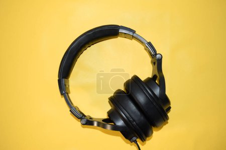 Photo for Top view black headphone with cable on yellow background - Royalty Free Image