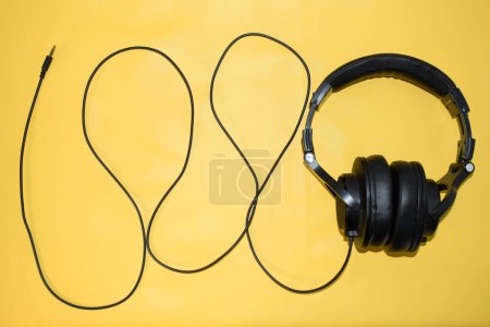 Photo for Top view black headphone with cable on yellow background - Royalty Free Image