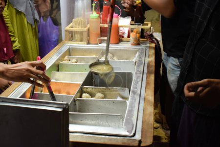 Téléchargez les photos : Tukang bakso ou vendeur de boulettes de viande pour préparer sa commande. boulette de viande indonesia ou Bakso, nourriture de rue indonesia - en image libre de droit