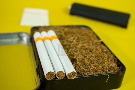Foto de Tabaco y cigarrillo en caja negra, rodillo de cigarrillo hecho a mano - Imagen libre de derechos