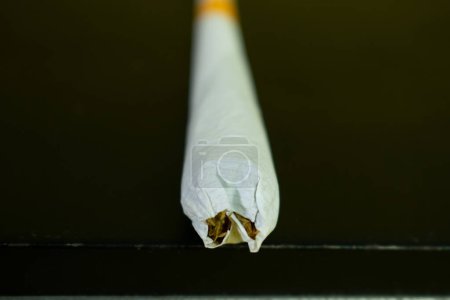 Téléchargez les photos : Gros plan cigarette fait à la main isolé sur fond noir - en image libre de droit