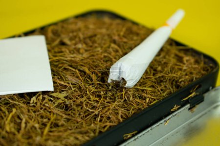 Foto de Cigarrillo laminado a mano y tabaco sobre fondo amarillo - Imagen libre de derechos